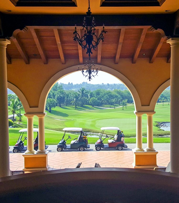 Golf carts stand by front of hotel near golf course