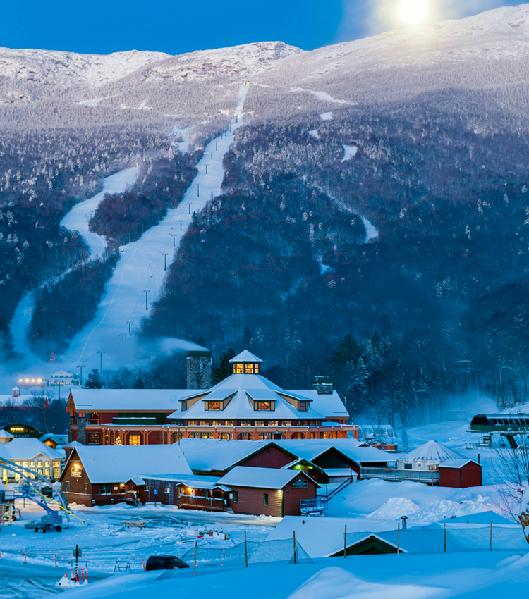 The moom setting behind the Mt. Mansfield, with ski resort at the base of the mountain in Stowe, Vermont.
