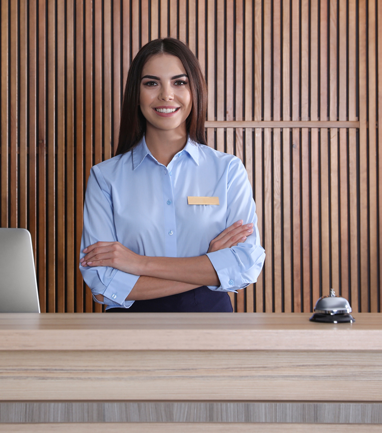 Portrait of a receptionist at desk in lobby in front of wood slatted wall