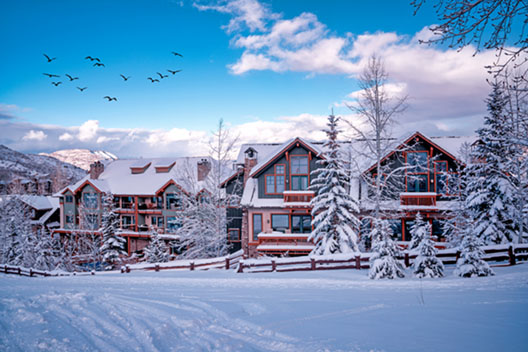 Ski resort in the Rocky Mountains with blue skies and clouds, birds flying overhead