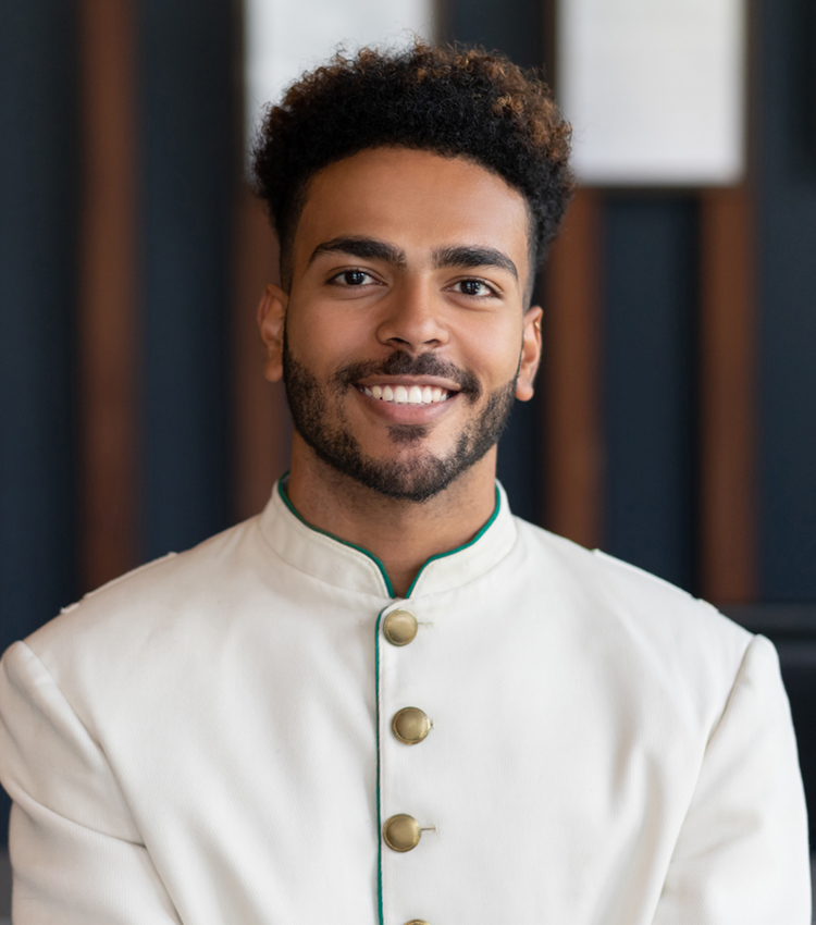 Portrait of black friendly bellhop working at hotel looking at camera very happy and smiling