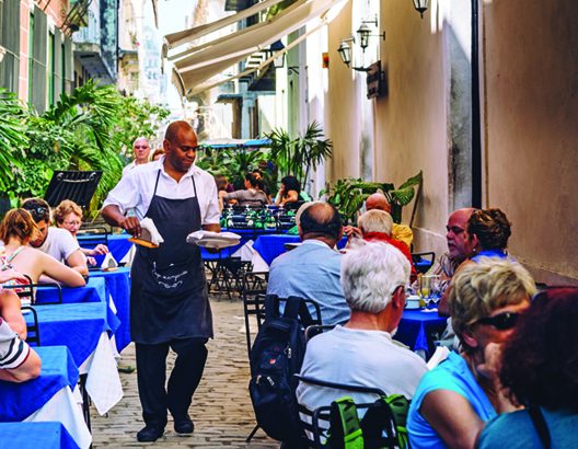 Waiter serving family at busy outdoor cafe.