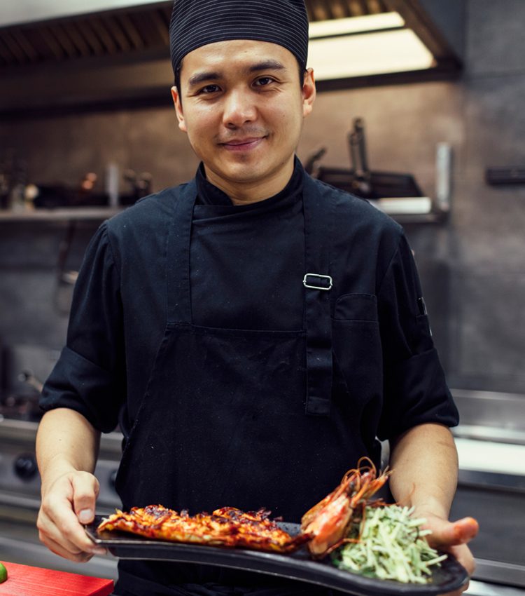 Smiling chef working in his kitchen in restaurant.