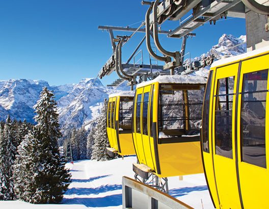 Yellow ski lifts at the top of the mountain with blue skies.